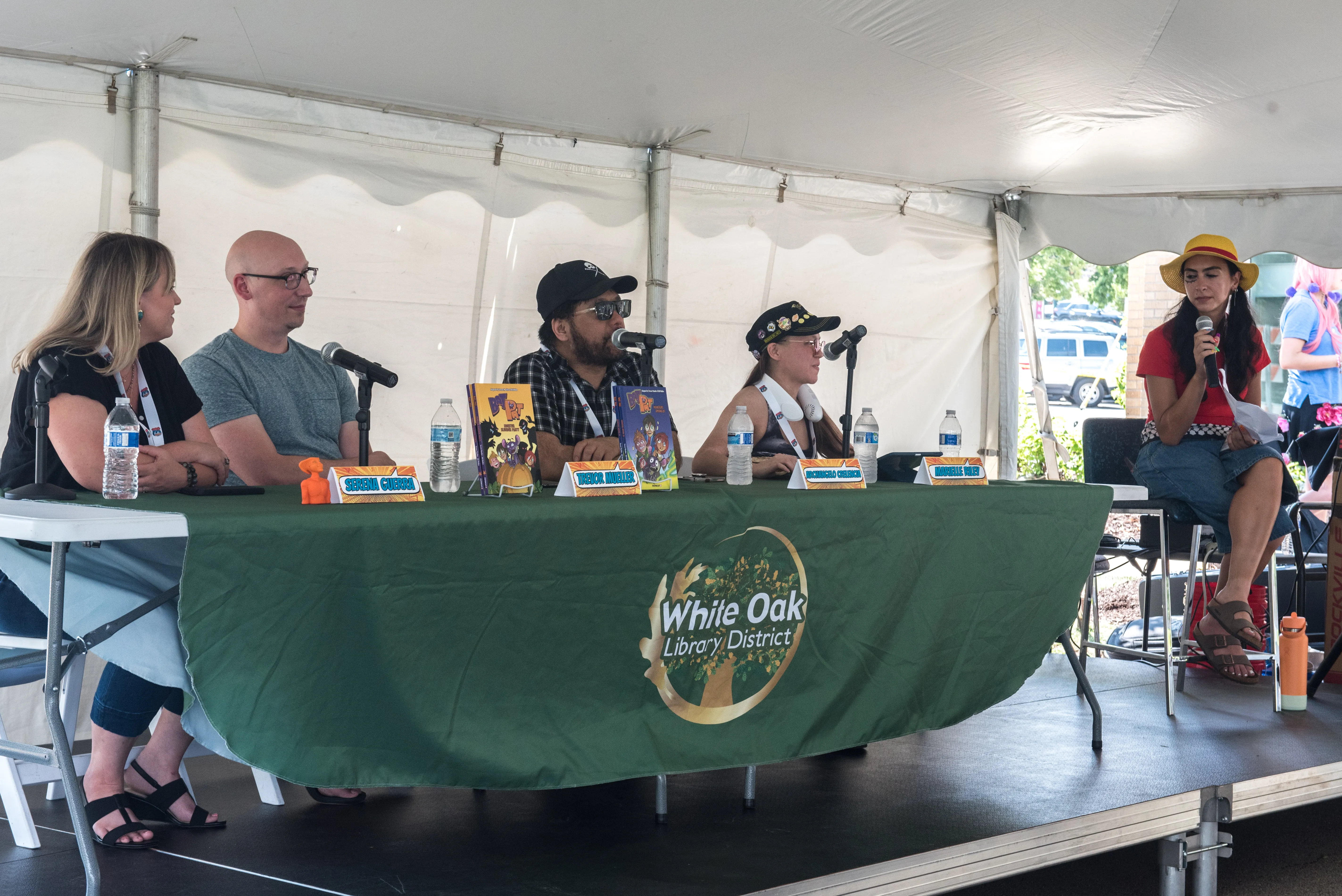 artist panel with 4 artists at table and moderator to side on chair
