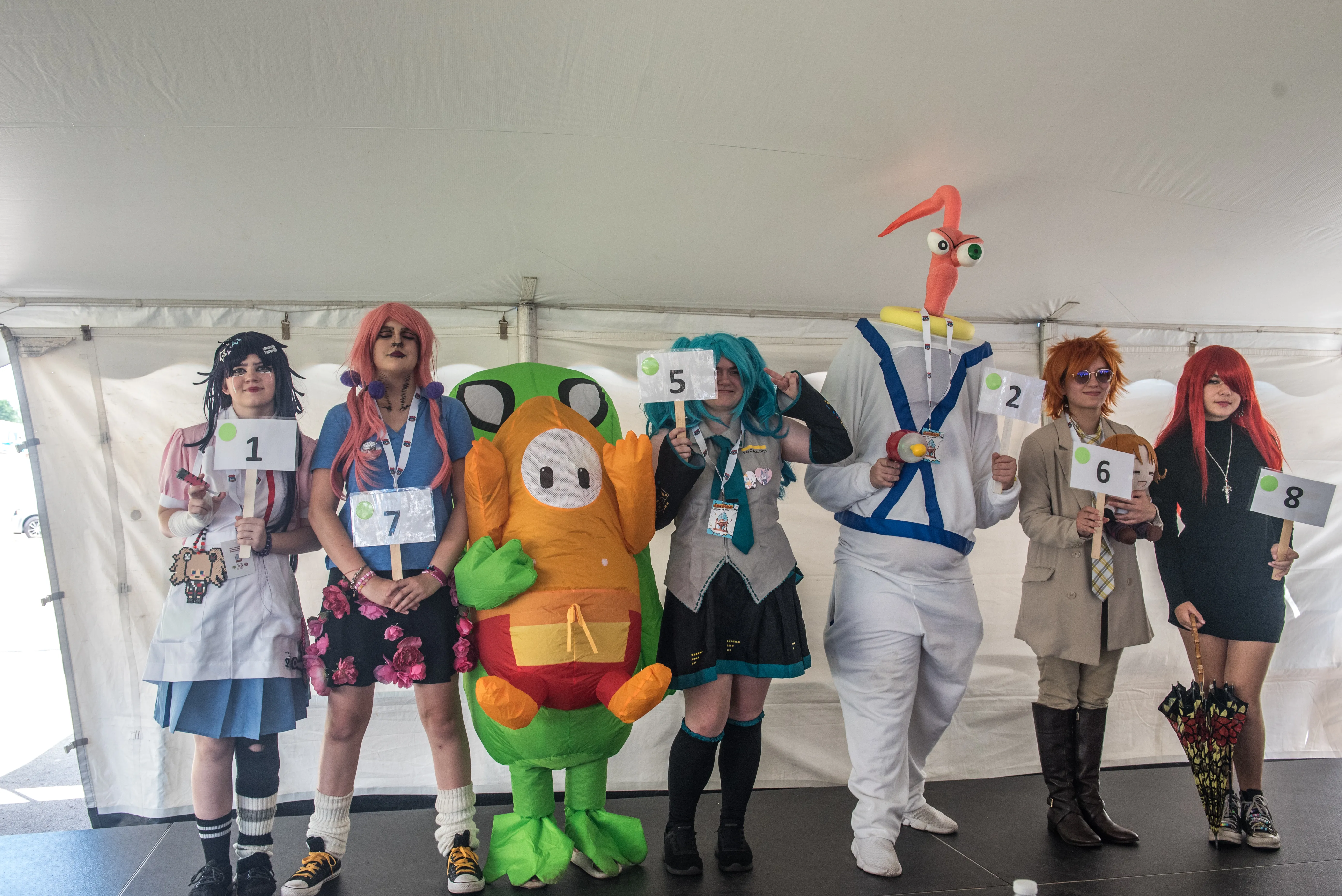 6 people in character costumes on stage with numbers