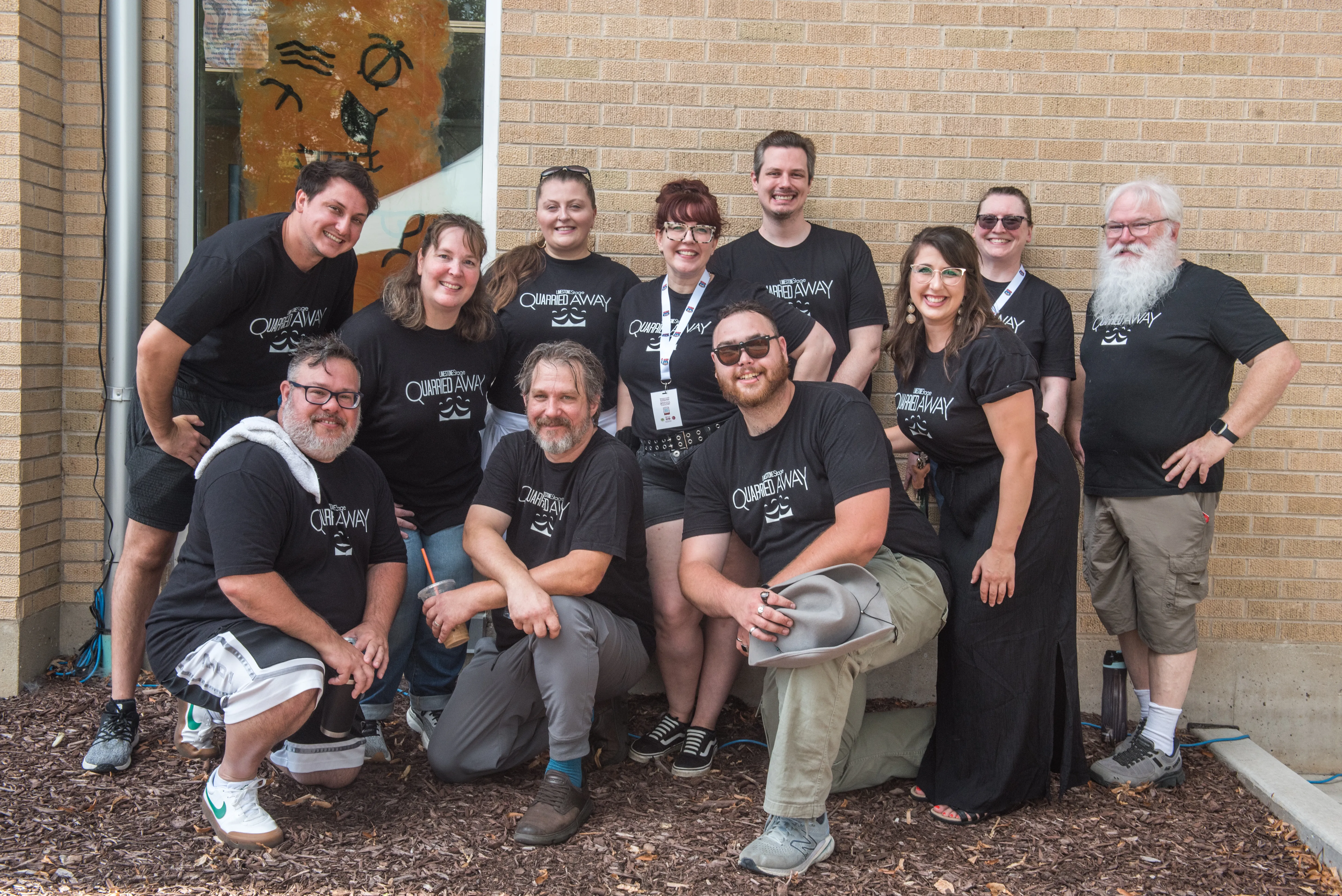 improv group taking picture in front of brick wall